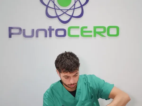 Una sala de fisioterapia de Punto Cero, con el logo en la pared y un fisioterapeuta tratando a una paciente