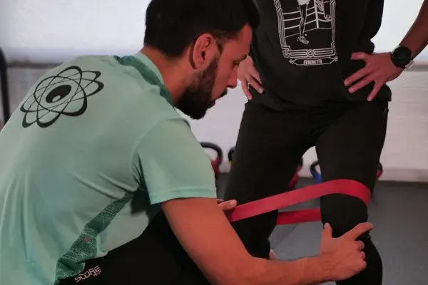 Massi Pereyra coloca una banda elástica en las rodillas de un cliente antes de un ejercicio de fuerza