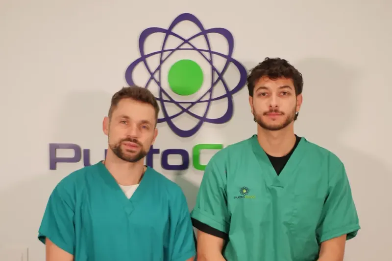 Ilya Mamontov y Víctor Marhuenda, los fisioterapeutas del centro, con el pijama verde delante del logo de Punto Cero