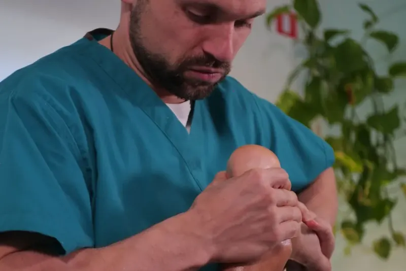 Un fisioterapeuta de Punto Cero moviliza con las dos manos el tobillo y el pie de un paciente